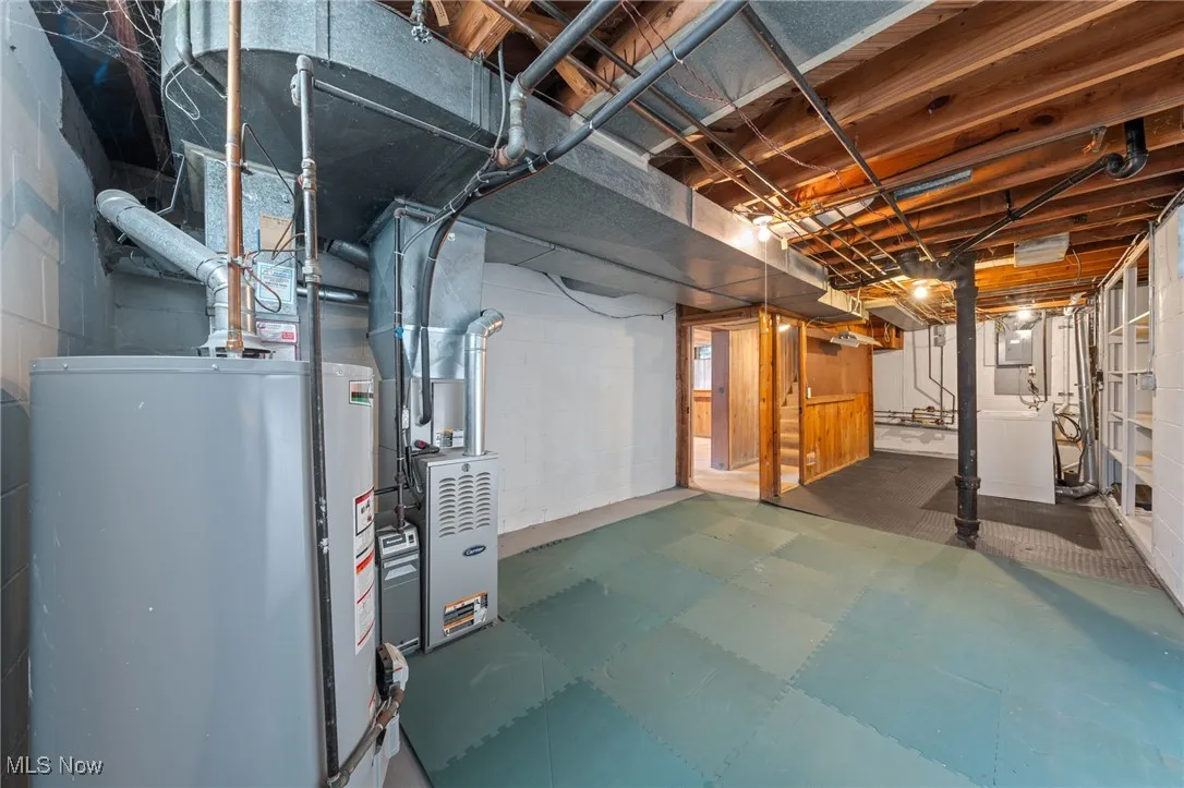 Unfinished basement featuring water heater, washer / dryer, heating unit, and tile patterned floors