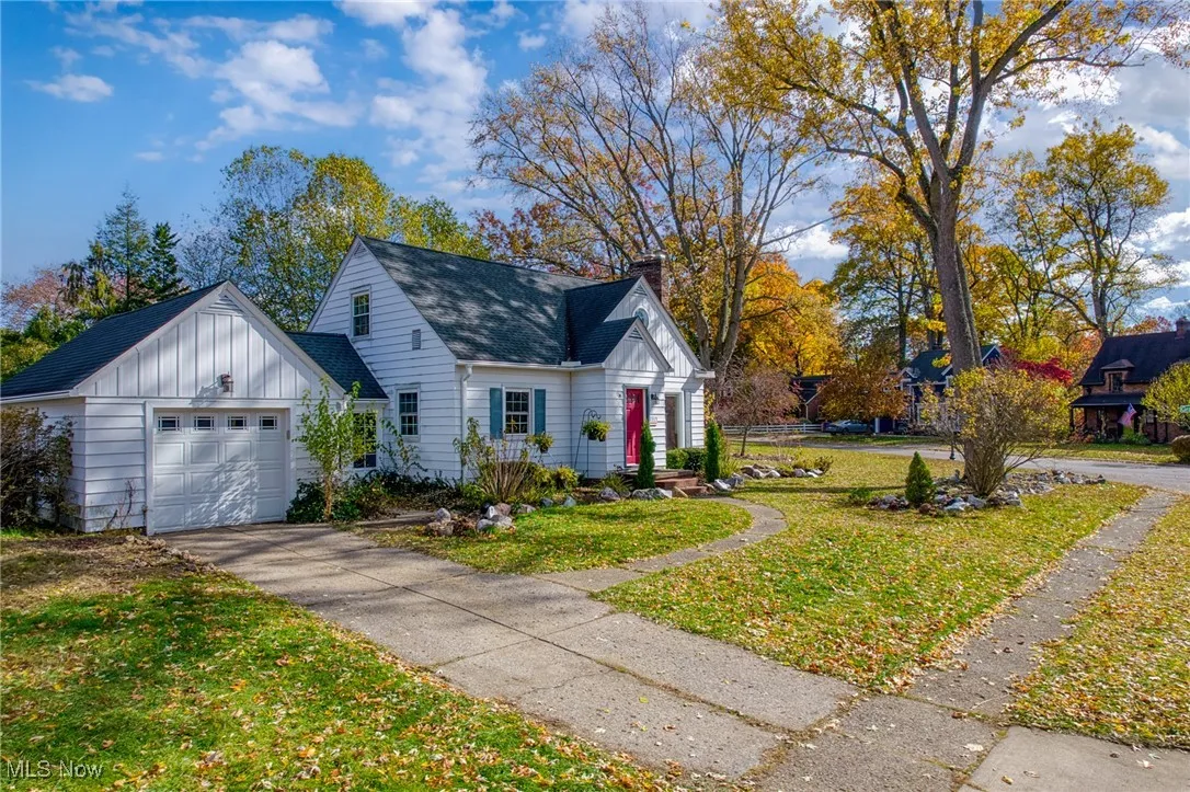 View of front of property with board and batten siding, a front yard, a chimney, a garage, and roof with shingles