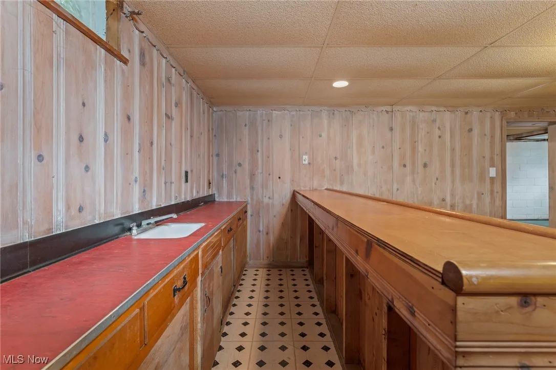 Bar area with wood walls, a paneled ceiling, dark countertops, light floors, and recessed lighting