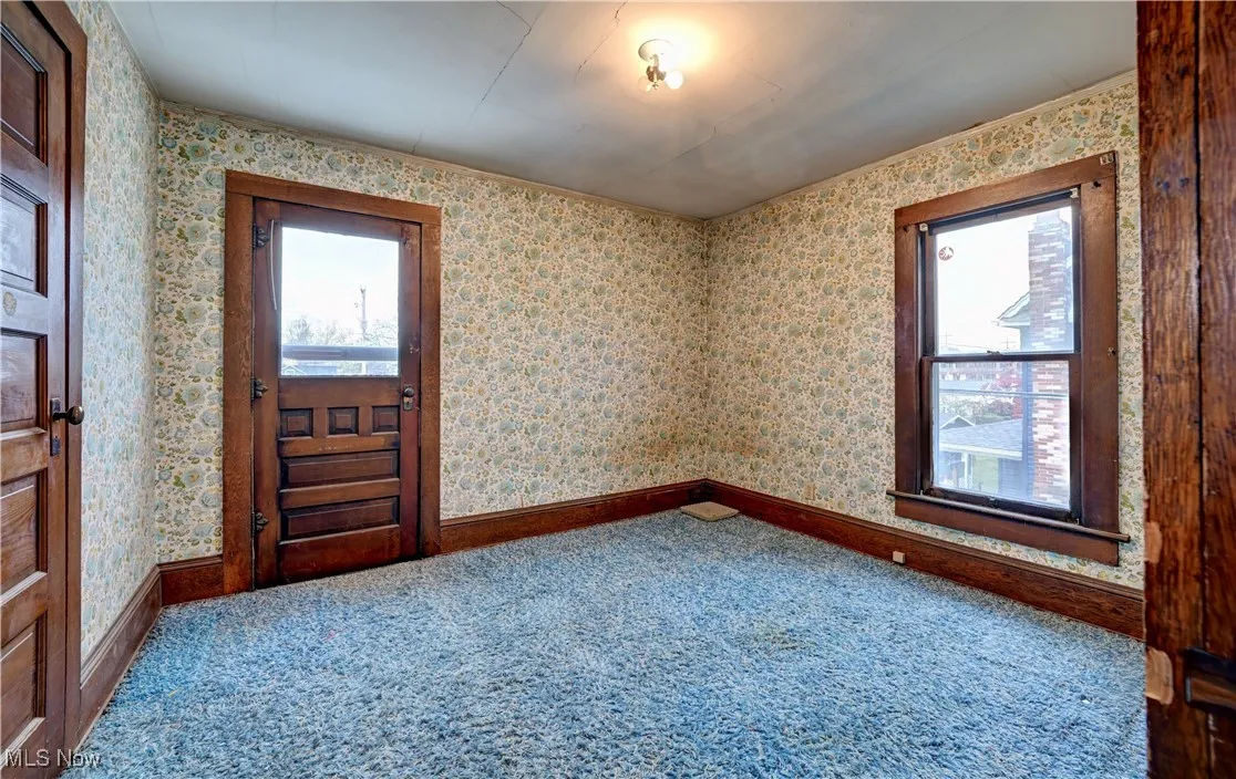 Carpeted entryway featuring plenty of natural light and wallpapered walls