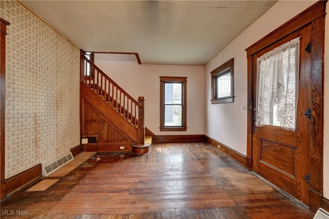 Foyer entrance with wood-type flooring, stairway, and wallpapered walls