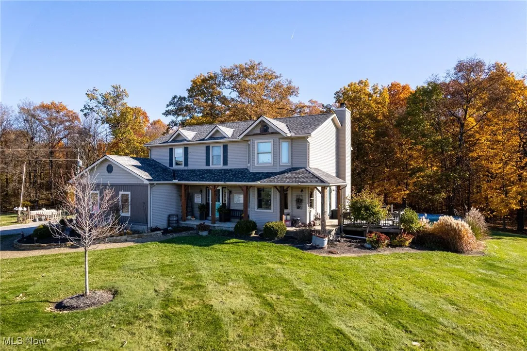 View of front of property with covered porch, a front yard, and a chimney