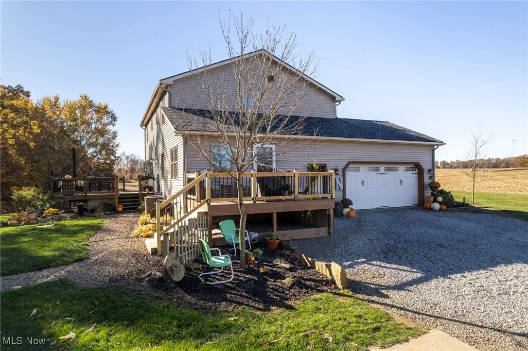 View of front facade with a wooden deck, driveway, a front yard, and an attached garage