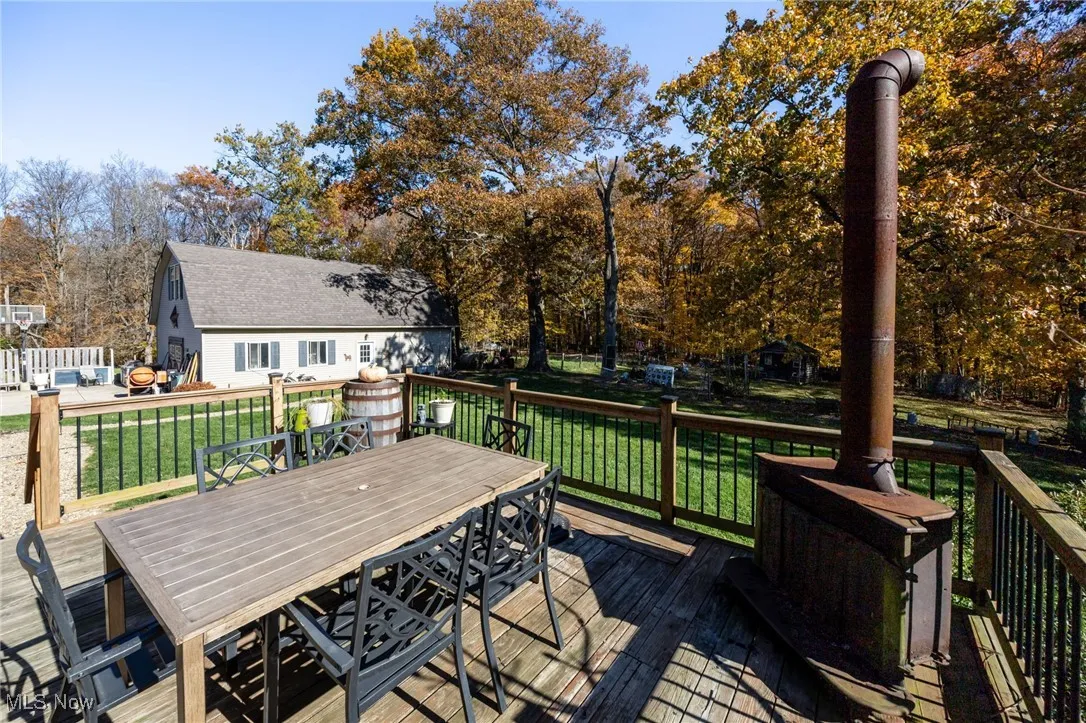Wooden deck with a yard, outdoor dining area, and view of scattered trees