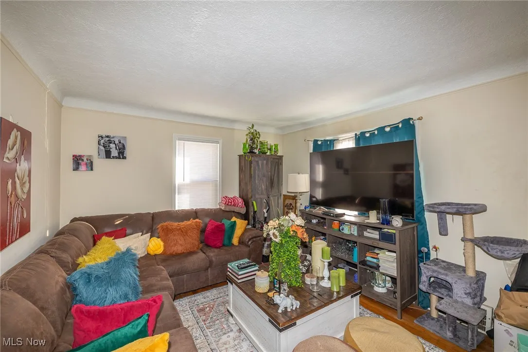 Living area featuring a textured ceiling, wood finished floors, and ornamental molding