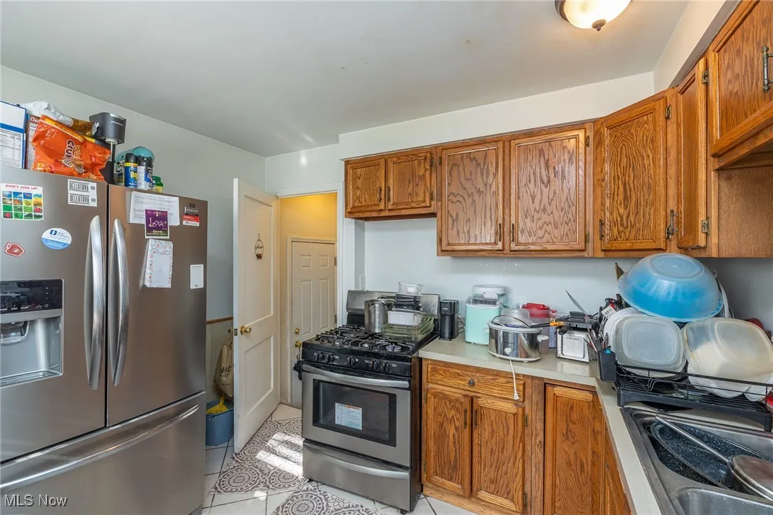 Kitchen featuring stainless steel appliances, brown cabinets, light countertops, and light tile patterned floors