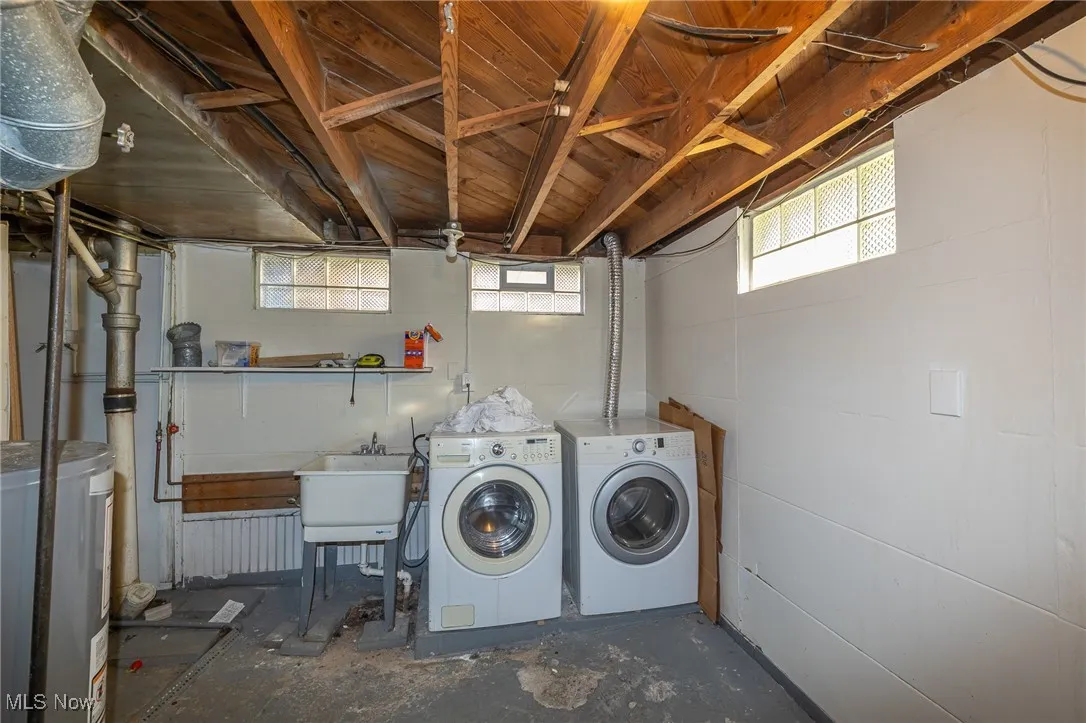 Washroom with concrete flooring, separate washer and dryer, and water heater