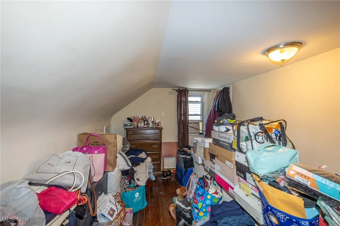Additional living space featuring dark wood finished floors and vaulted ceiling