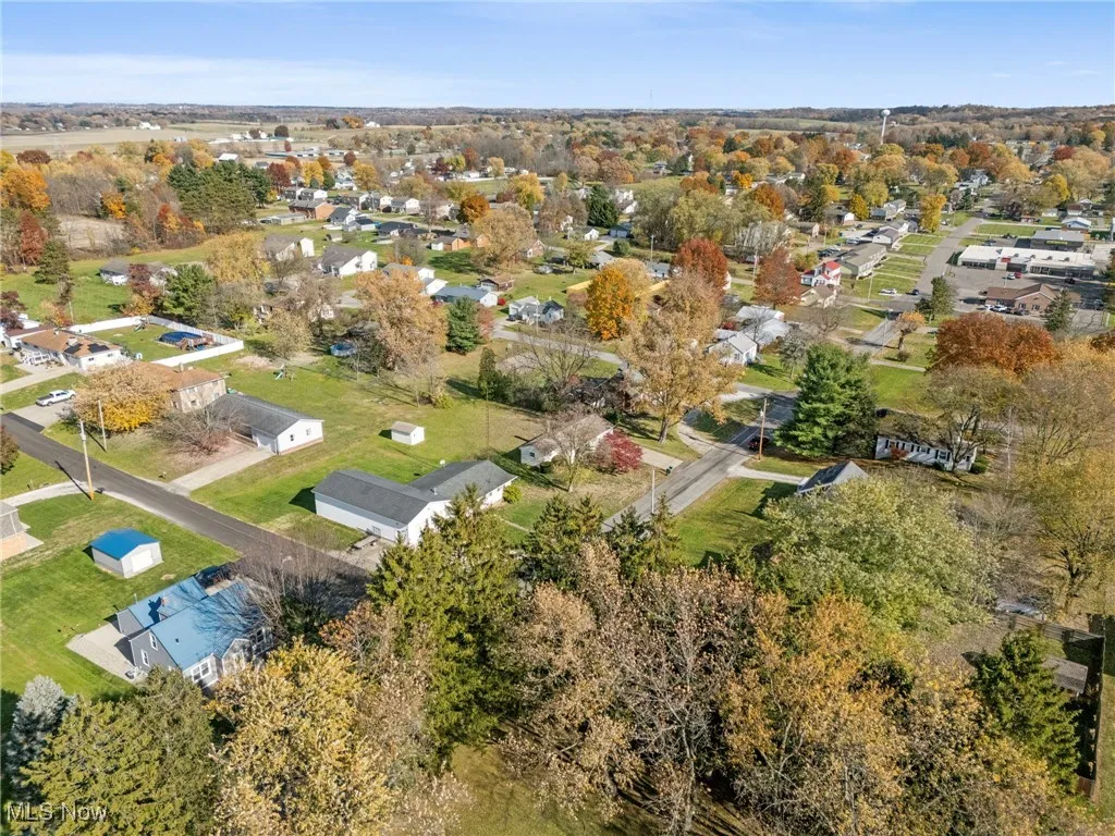 Aerial view of property and surrounding area featuring nearby suburban area and a tree filled landscape