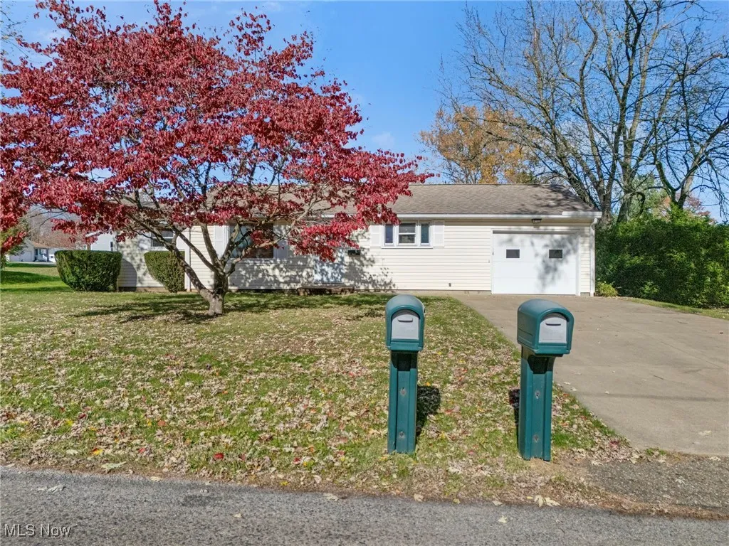 Ranch-style house featuring concrete driveway, a garage, and a front yard