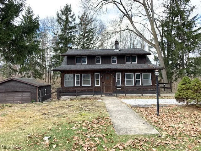View of front of home featuring an outbuilding, a chimney, a detached garage, and a front yard
