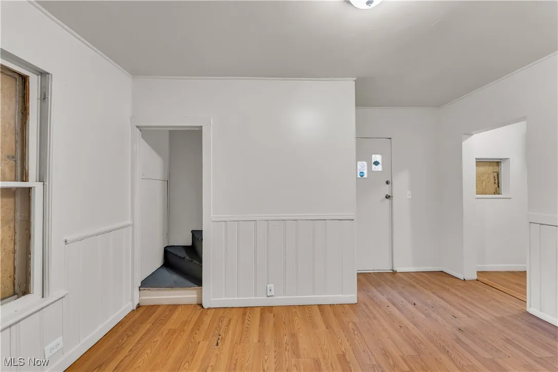 Entrance foyer featuring wood finished floors, wainscoting, and ornamental molding