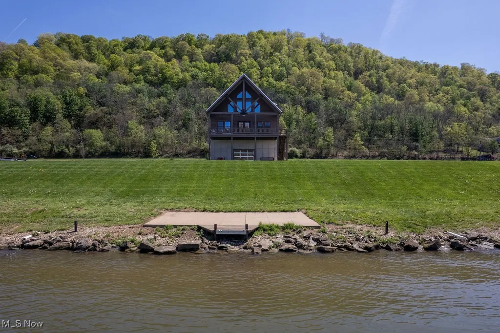 View of river side w/ nice concrete pad where the portable dock is installed and shows the elevation of home.