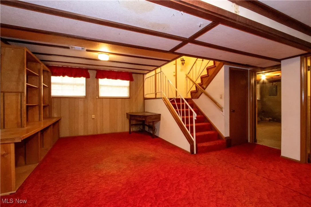 Below grade area featuring stairs, dark colored carpet, and wood walls