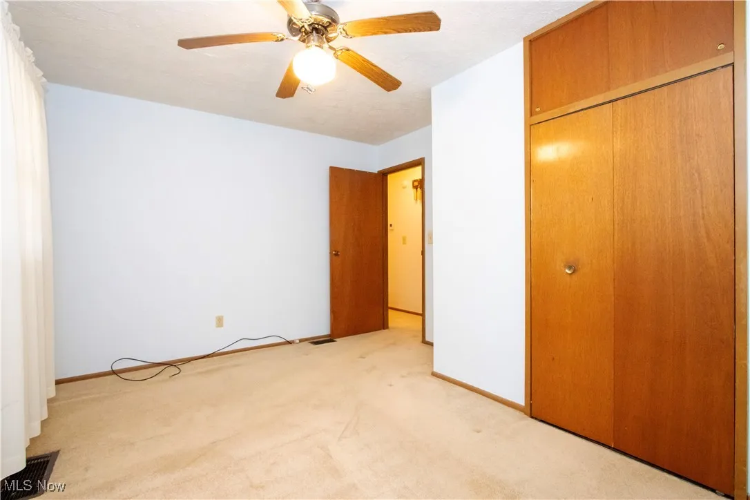 Unfurnished bedroom with light colored carpet, ceiling fan, and a closet