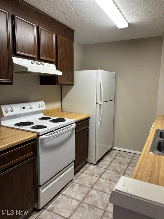 Kitchen with white range, extractor fan, a textured ceiling, dark brown cabinets