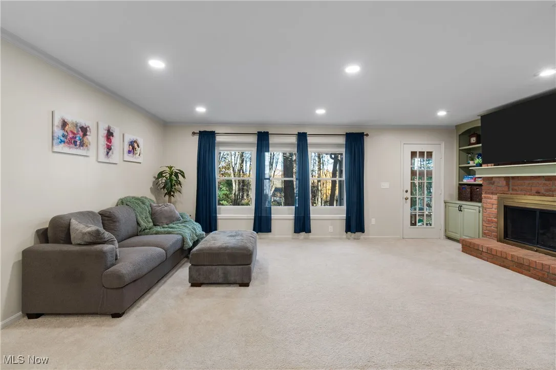 Living room with light carpet, recessed lighting, a brick fireplace, and crown molding