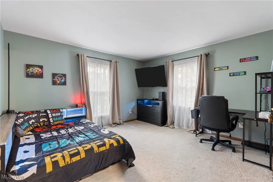 Bedroom featuring light carpet, multiple windows, and an office area