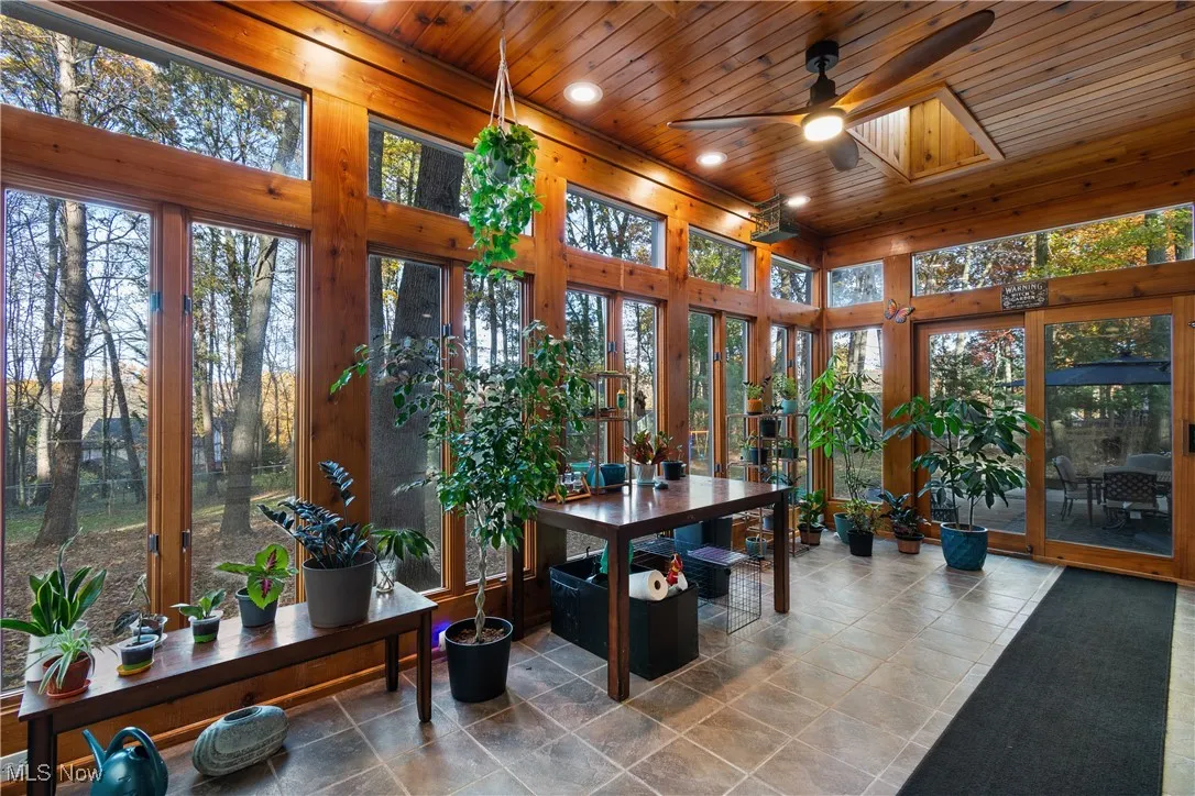 Sunroom with wooden ceiling, plenty of natural light, tile patterned flooring, recessed lighting, and a towering ceiling