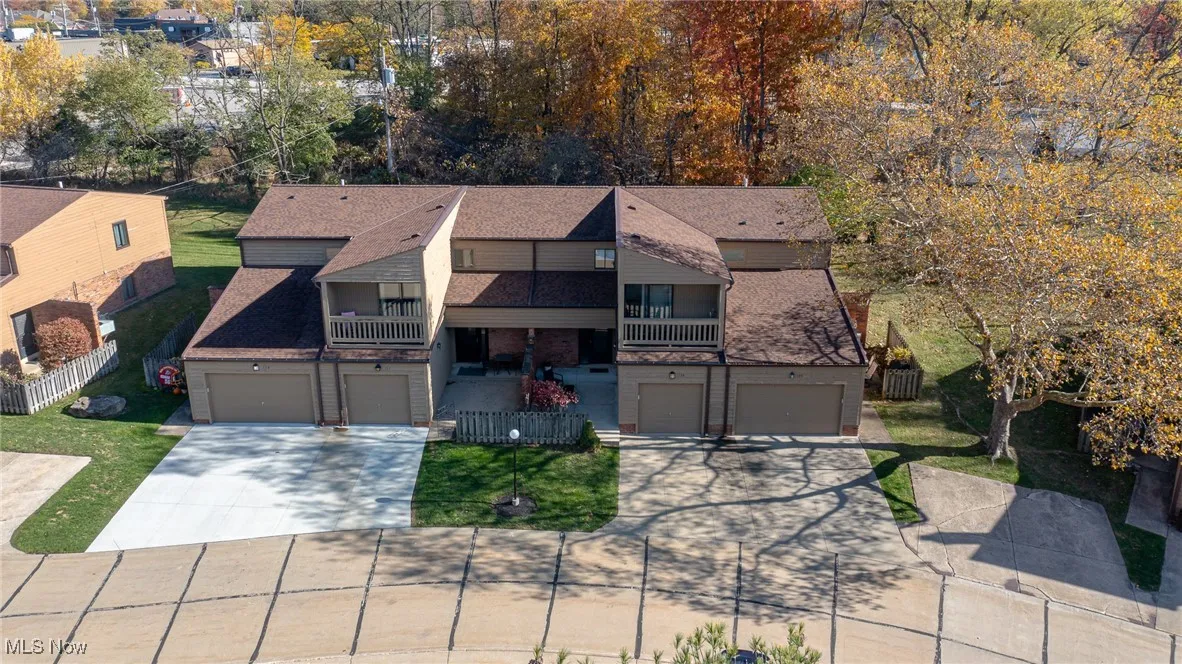 View of front facade featuring a balcony, driveway, brick siding, and roof with shingles