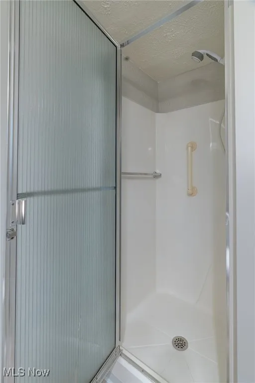 Bathroom with a stall shower and a textured ceiling