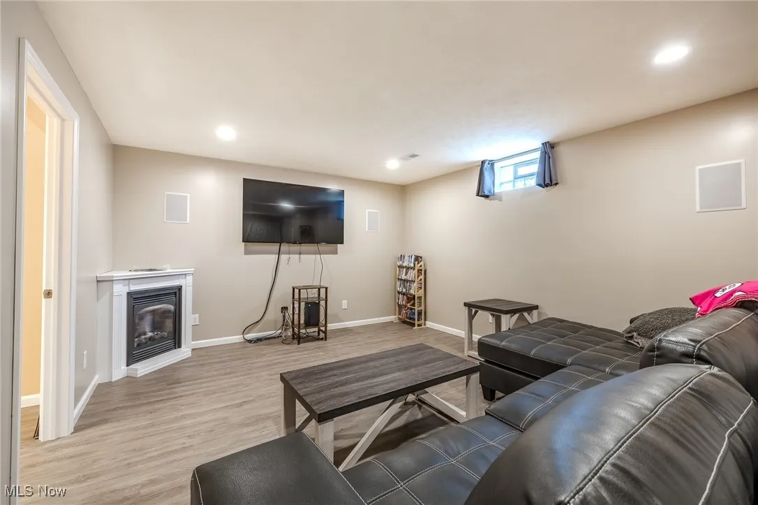Living room with a glass covered fireplace, light wood-style flooring, and recessed lighting