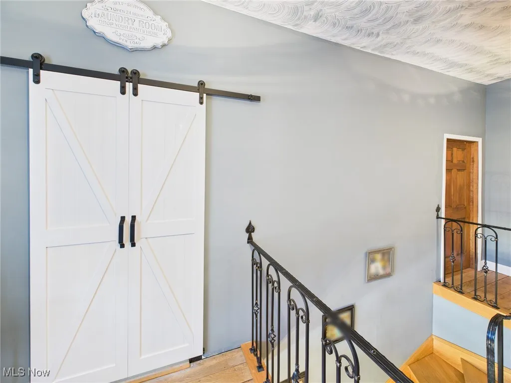 Stairs with wood finished floors and a barn door