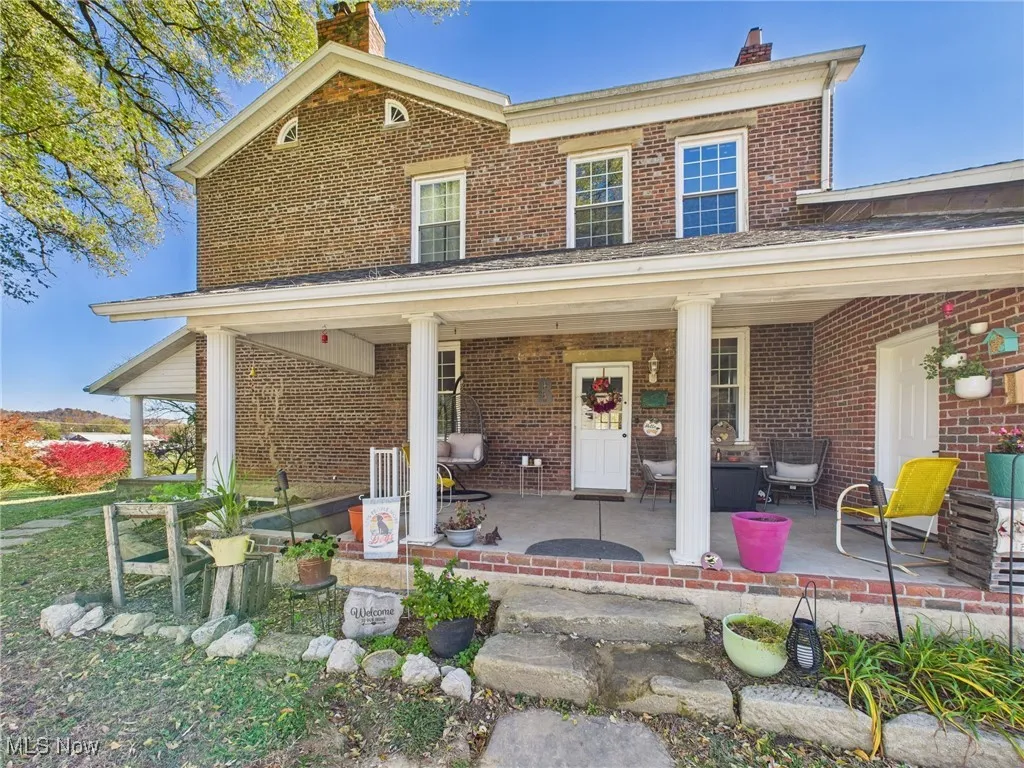 View of front of home featuring a chimney, brick siding, and a porch