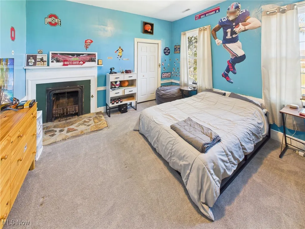 Bedroom featuring carpet, a closet, and a fireplace with raised hearth