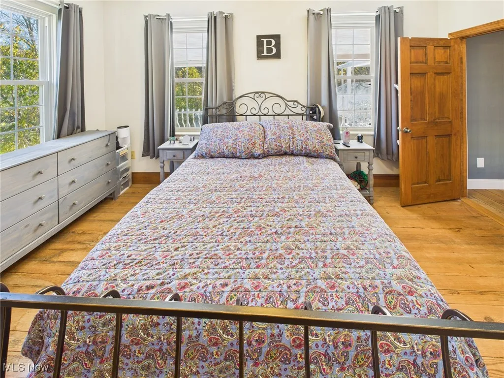 Bedroom with multiple windows and light wood-style floors