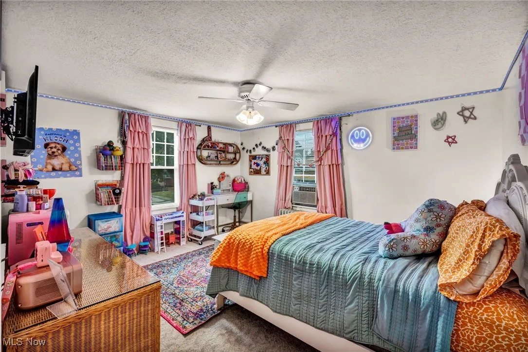 Carpeted bedroom featuring a textured ceiling and a ceiling fan
