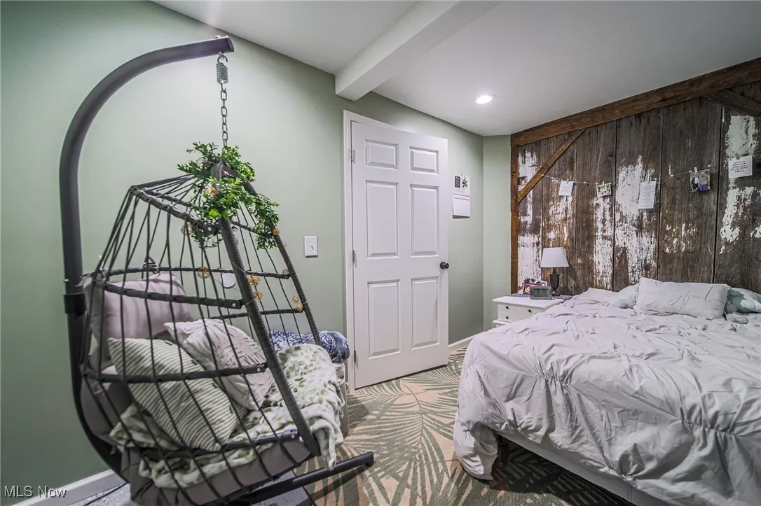 Bedroom featuring beamed ceiling, wood walls, and recessed lighting
