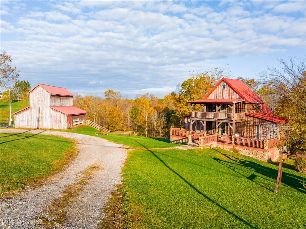 View of dirt / gravel driveway featuring a barn and a wooded view