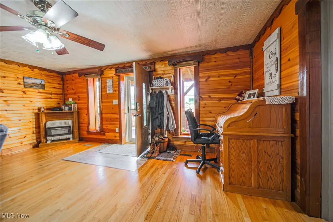 Office with wood walls, light wood-style flooring, an ornate ceiling, and heating unit