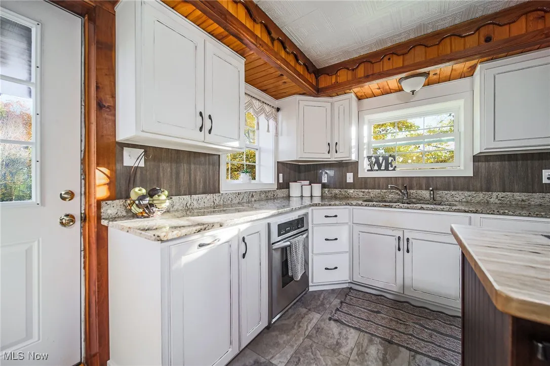 Kitchen with butcher block countertops, white cabinets, wood walls, and stainless steel oven