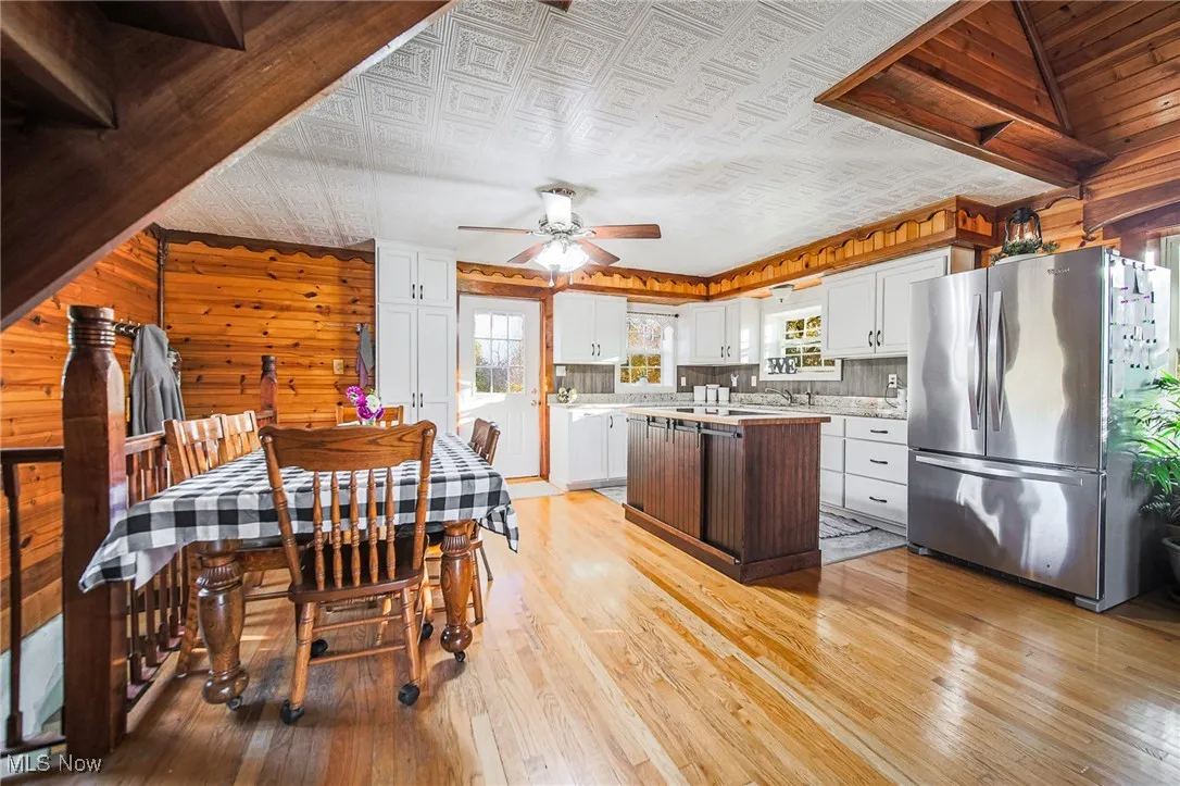 Kitchen featuring freestanding refrigerator, light countertops, light wood-style floors, an ornate ceiling, and wooden walls