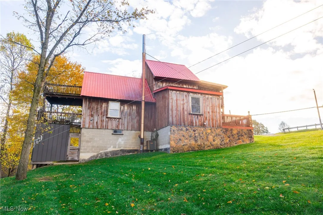 View of home's exterior with stairway, a lawn, a deck, and a metal roof