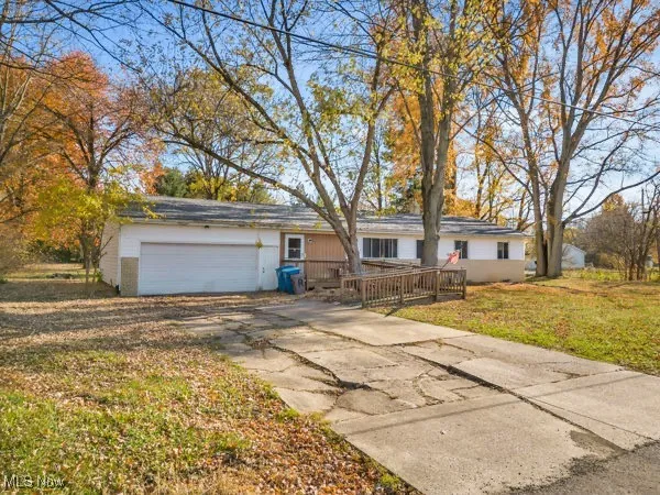 Single story home with a front yard, driveway, an attached garage, and a wooden deck