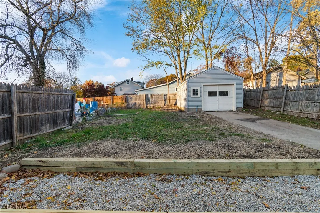 Fenced backyard featuring an outbuilding, a detached garage, and concrete driveway