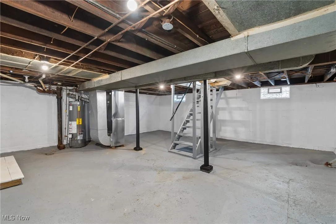 Below grade area featuring stairs, heating unit, and gas water heater