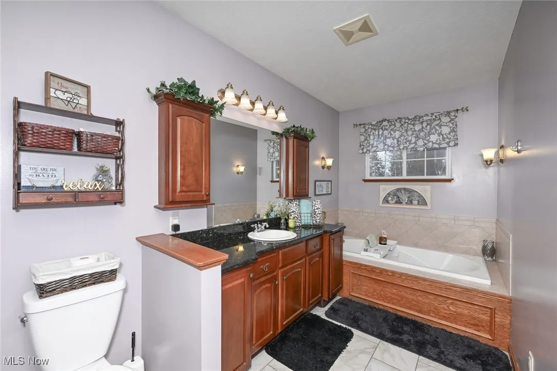 Full bath featuring vanity with granite countertop and a whirlpool bath