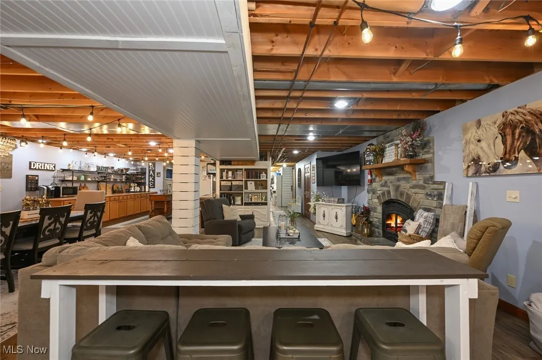 Indoor bar featuring a fireplace, dark wood-style flooring, and dark countertops