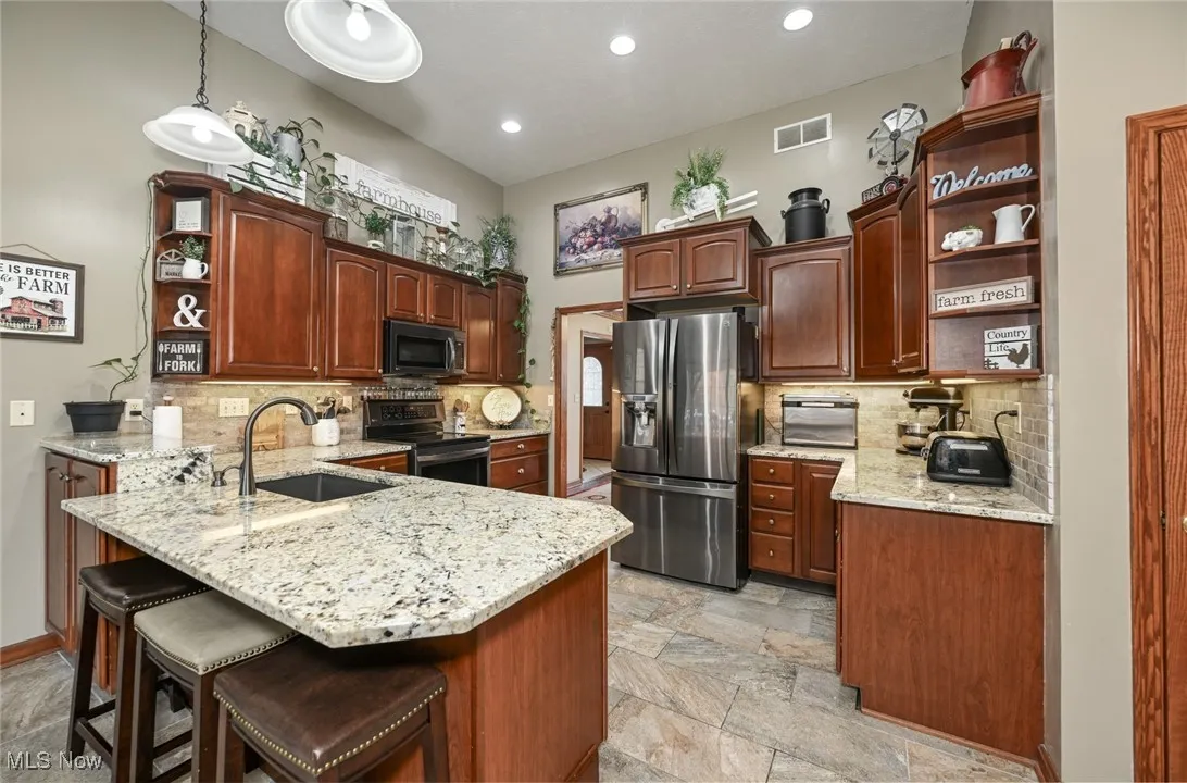 Kitchen with open shelves, backsplash, appliances with stainless steel finishes.
