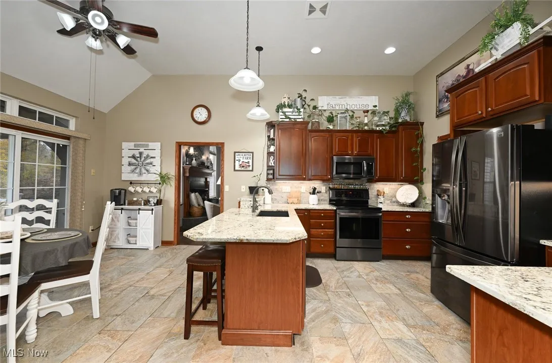 Kitchen with stainless steel appliances, pendant lighting, a peninsula, backsplash, and granite counters