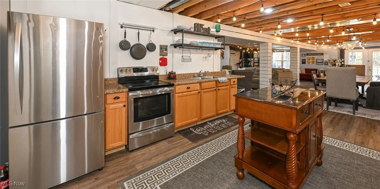 Lower-level kitchen featuring stainless steel appliances, dark wood-type flooring, open shelves, and accent lighting