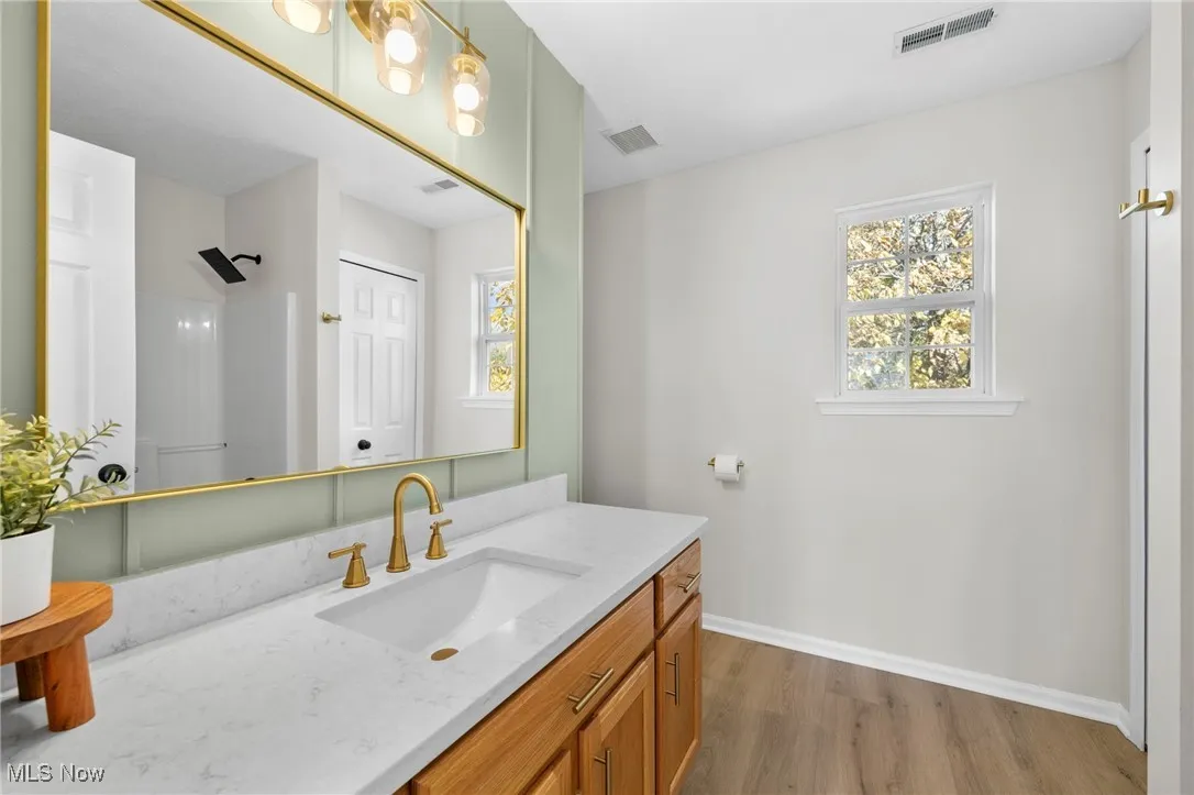 Bathroom with light wood-style floors, vanity, and a shower