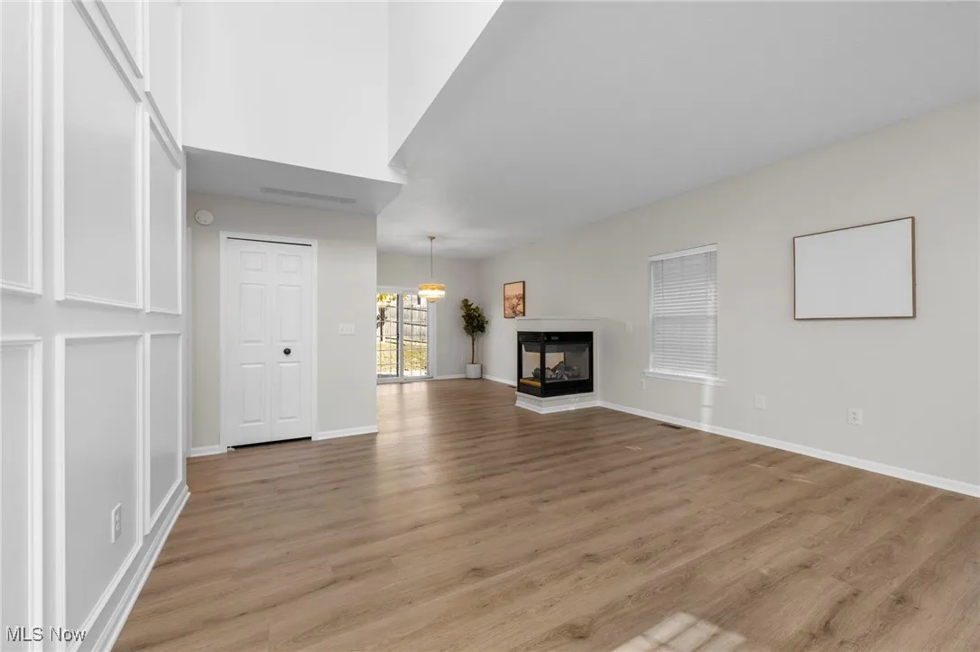 Unfurnished living room with light wood finished floors and a multi sided fireplace