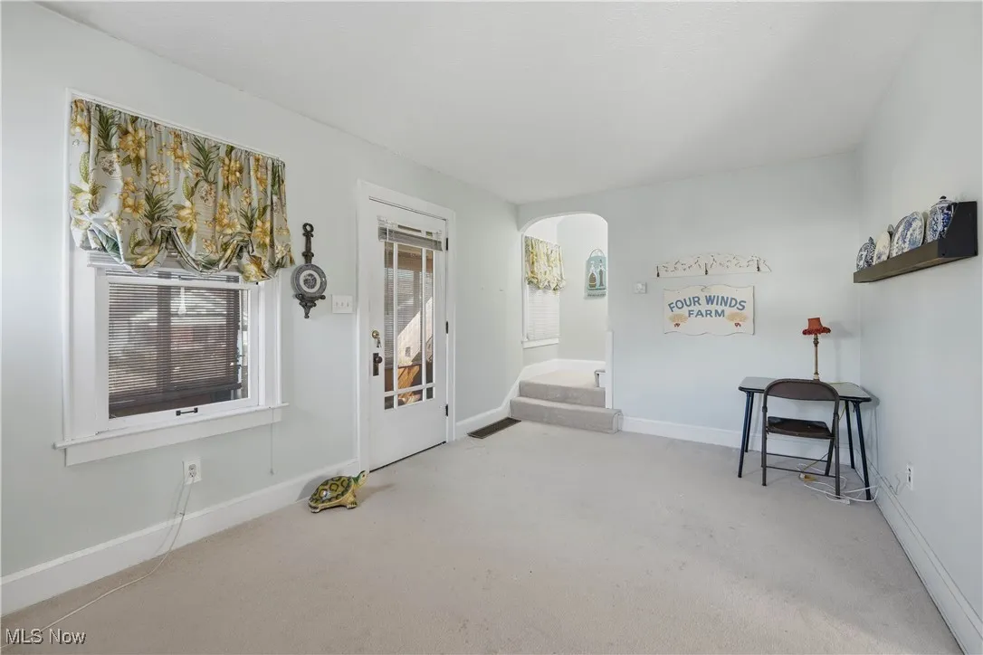 Foyer entrance featuring arched walkways, carpet flooring, and stairs