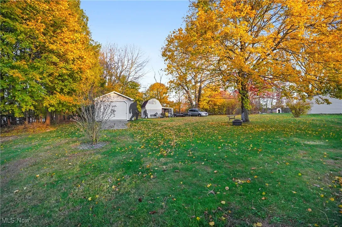 View of grassy yard featuring an outbuilding and a detached garage