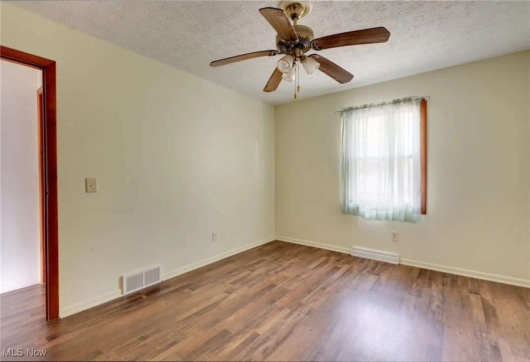 Bedroom with a textured ceiling, wood style floors, and ceiling fan